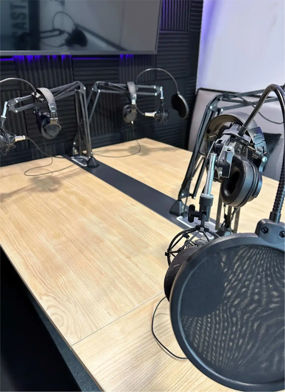 inside the podcast studio: table, mics, tv