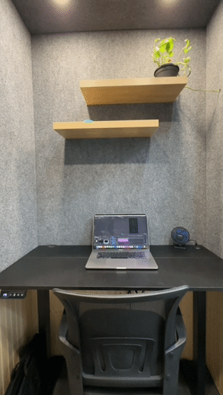inside the work pod, small space, wood accents, standing desk, shelf with plant
